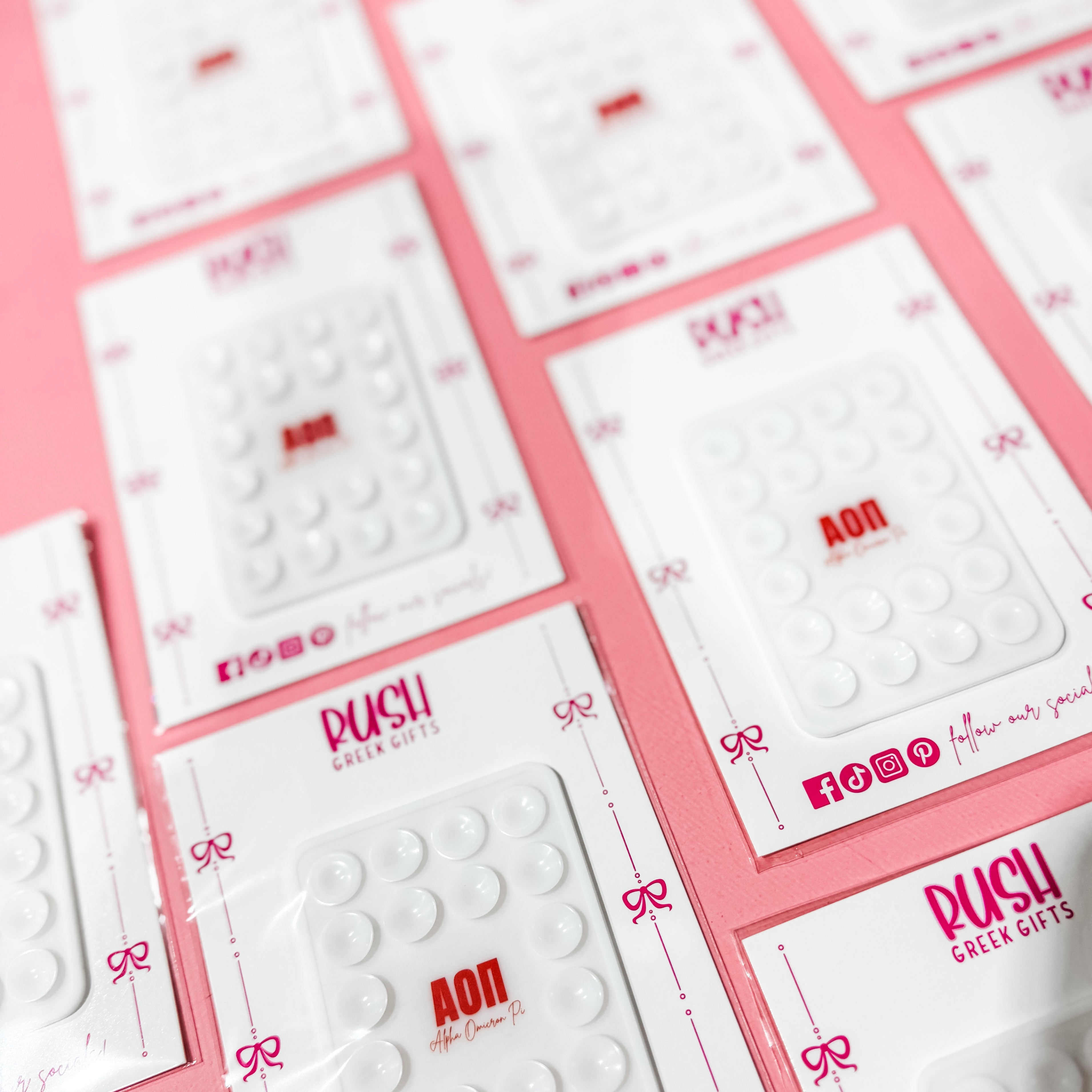 Multiple white cards with red text and 'RUSH' branding on a pink background. Alpha Omicron Pi