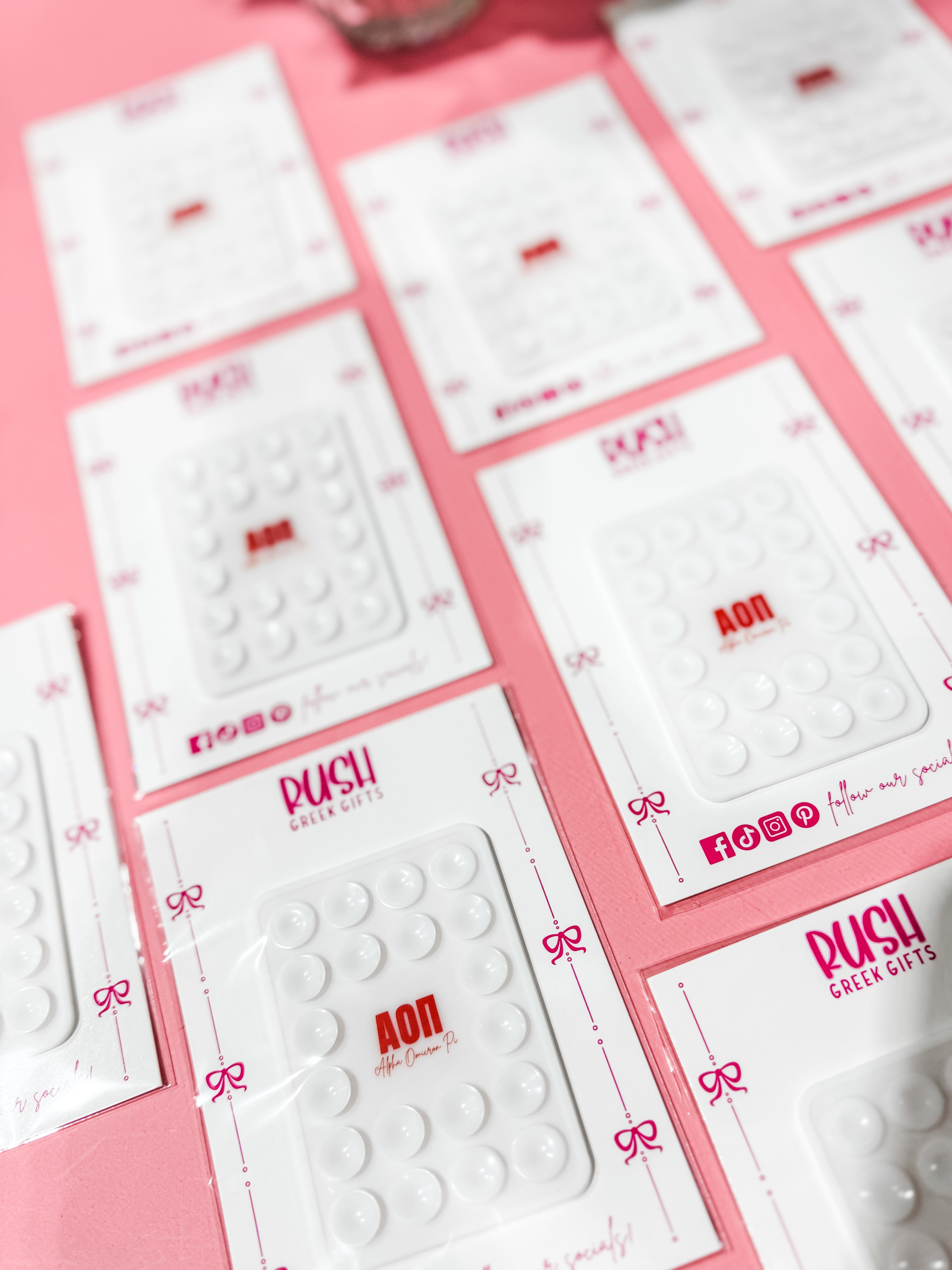 Multiple white cards with red text and 'RUSH' branding on a pink background. Alpha Omicron Pi