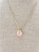 Alpha Chi Omega enamel pendant necklace on a beige fabric background