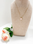 Alpha Chi Omega enamel pendant necklace on a mannequin bust with flowers on a white background