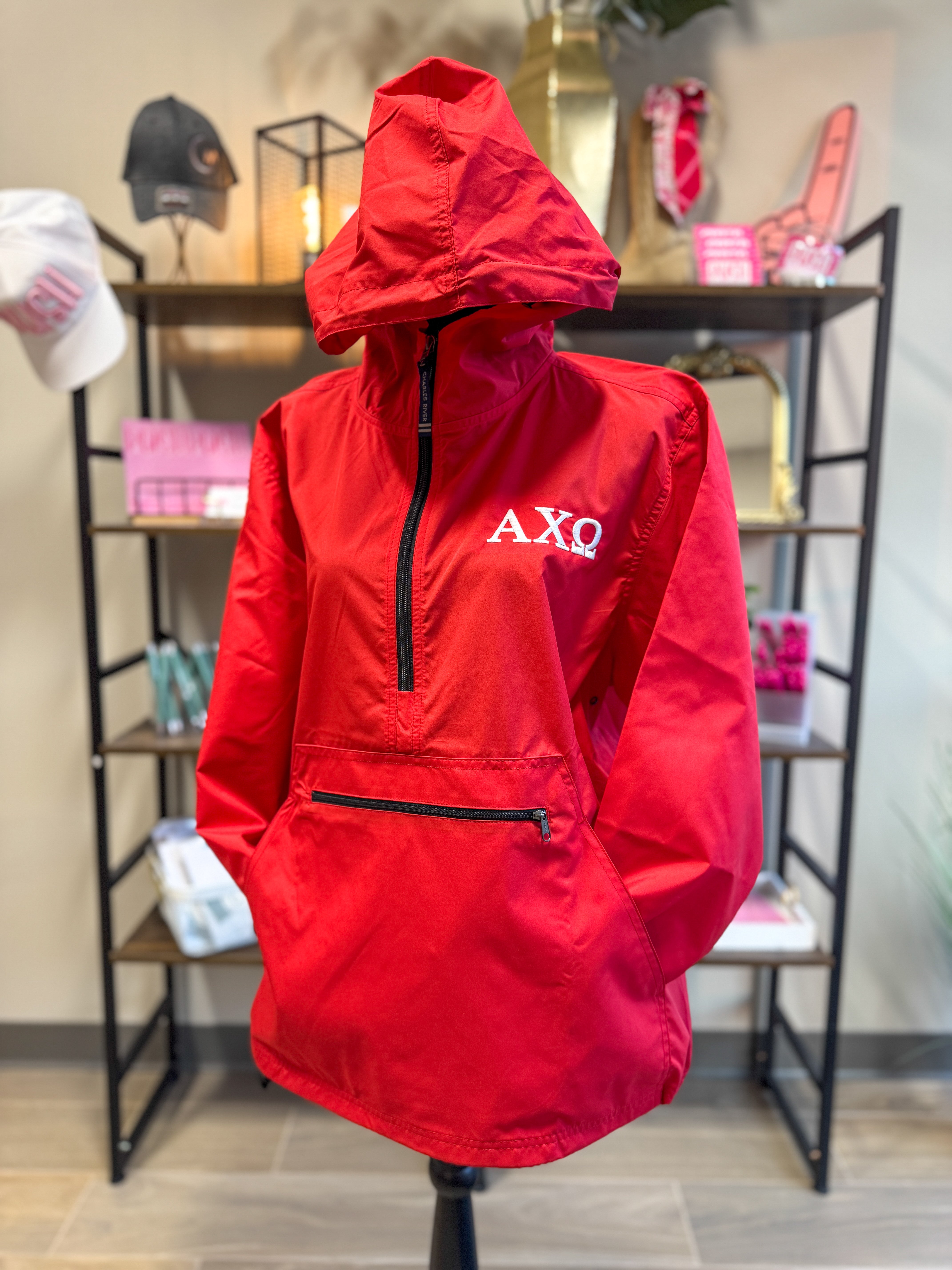 Red Alpha Chi Omega rain jacket with AXO logo on a mannequin in a store setting